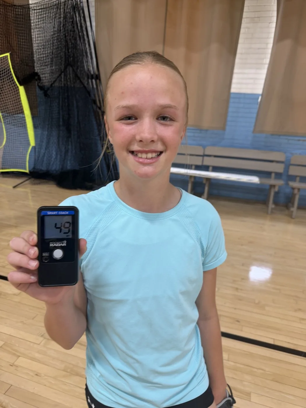 A Staggs Performance Lab athlete holding up a radar readout after a pitching session
